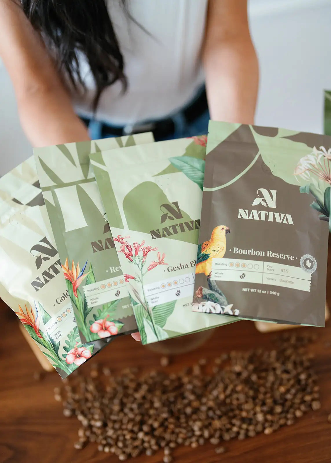 Collection of Nativa coffee packages on a wooden surface with a blurred person in the background.