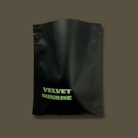 Black pouch with 'Velvet Sunrise Coffee' text on a brown background